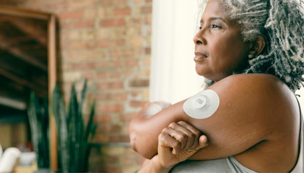 Person wearing a continuous glucose monitor on their hand, monitoring blood sugar levels in real-time.